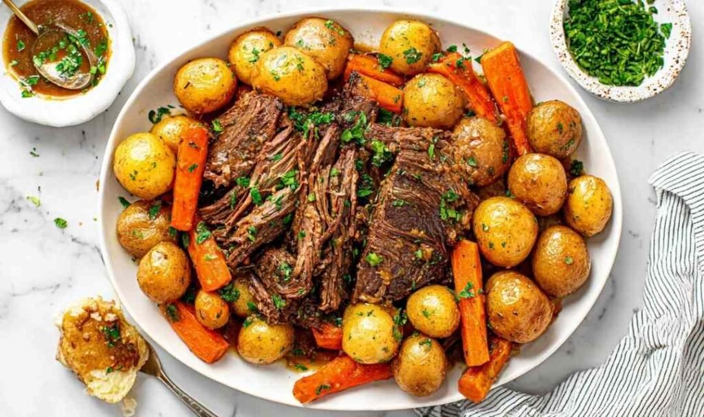Tender crock pot pot roast with carrots, potatoes, and fresh herbs in a slow cooker, ready to serve