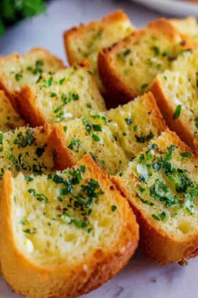 Golden garlic bread with sliced bread on a baking sheet fresh from the oven with crispy edges and garlic butter topping