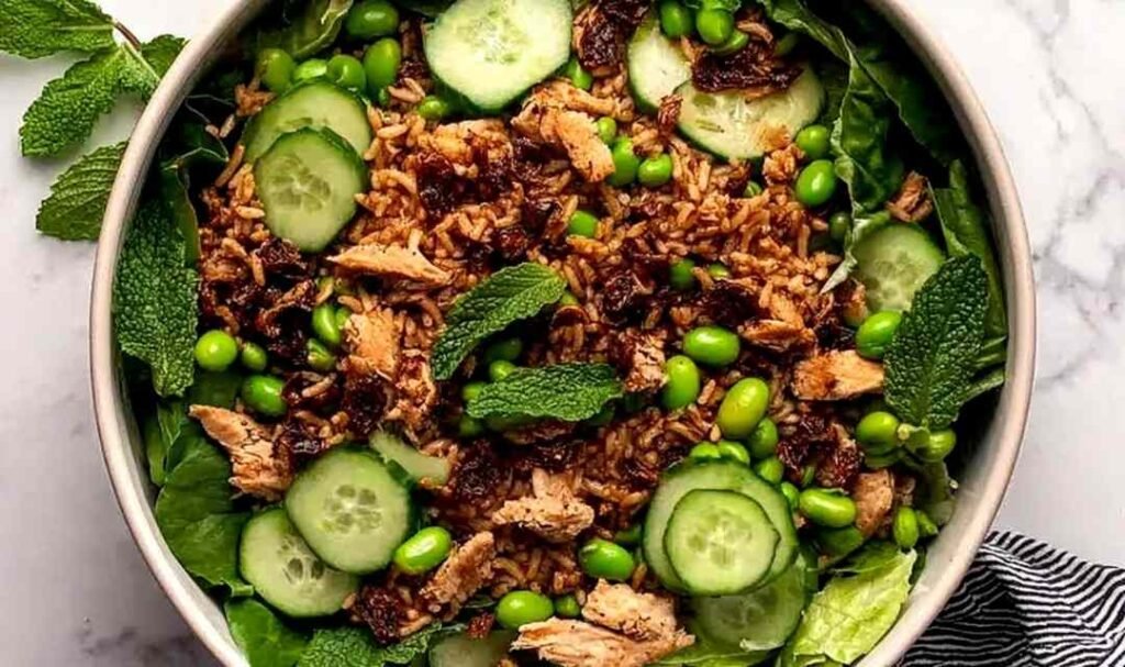 High protein crispy rice salad bowl with golden chicken, edamame, cucumbers, mint, and cilantro lime tahini dressing