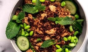 High protein crispy rice salad bowl with golden chicken, edamame, cucumbers, mint, and cilantro lime tahini dressing