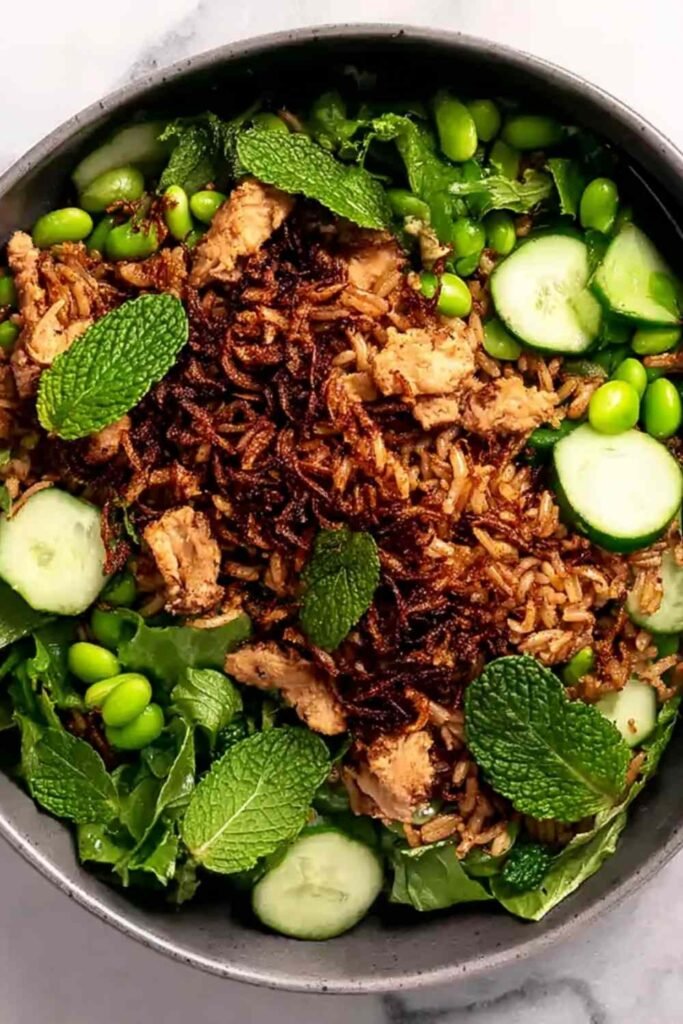 High protein crispy rice salad bowl with golden chicken, edamame, cucumbers, mint, and cilantro lime tahini dressing