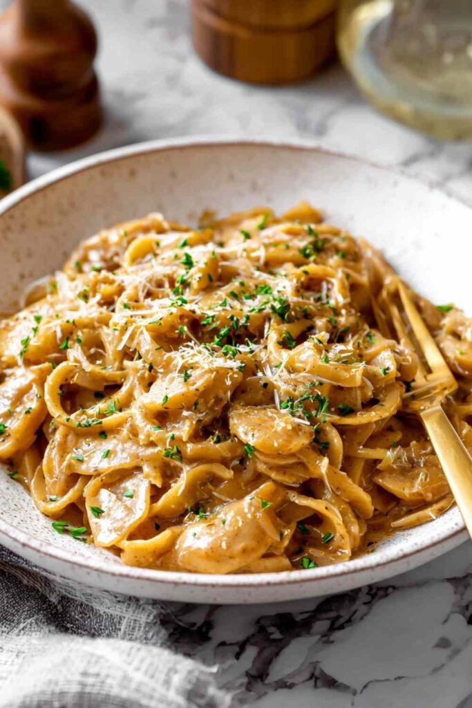 One pot French onion pasta with caramelized onions and melted Gruyere cheese served in white bowl for easy weeknight dinner