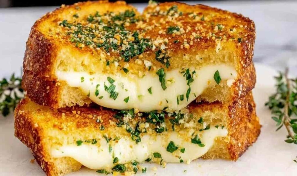 Garlic bread grilled cheese sandwich sliced diagonally showing a gooey mozzarella and cheddar cheese pull on a wooden board
