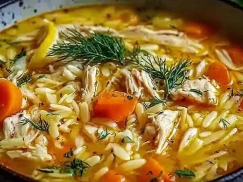 Bowl of Greek lemon chicken soup with orzo pasta, shredded chicken, vegetables, and fresh parsley garnish