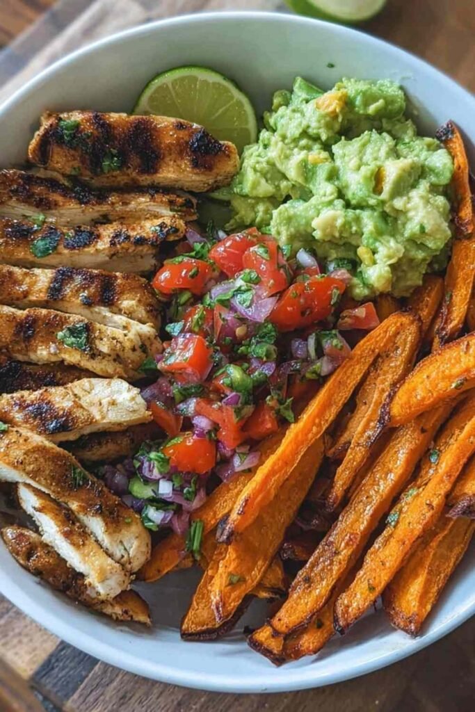 grilled herb chicken bowl with sweet potato fries and avocado salsa over quinoa with greens