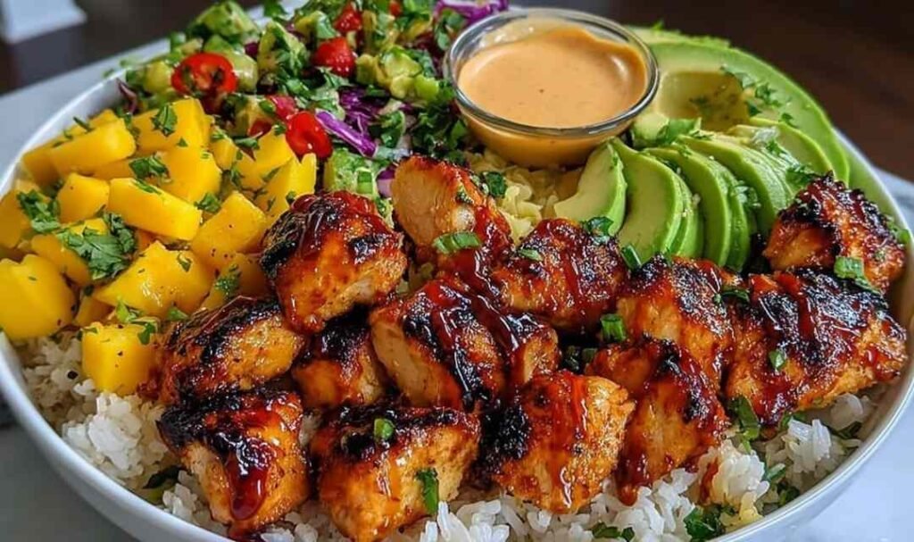 Grilled maple sriracha chicken bowl with coconut rice, fresh mango avocado salsa, and chili mayo swirl