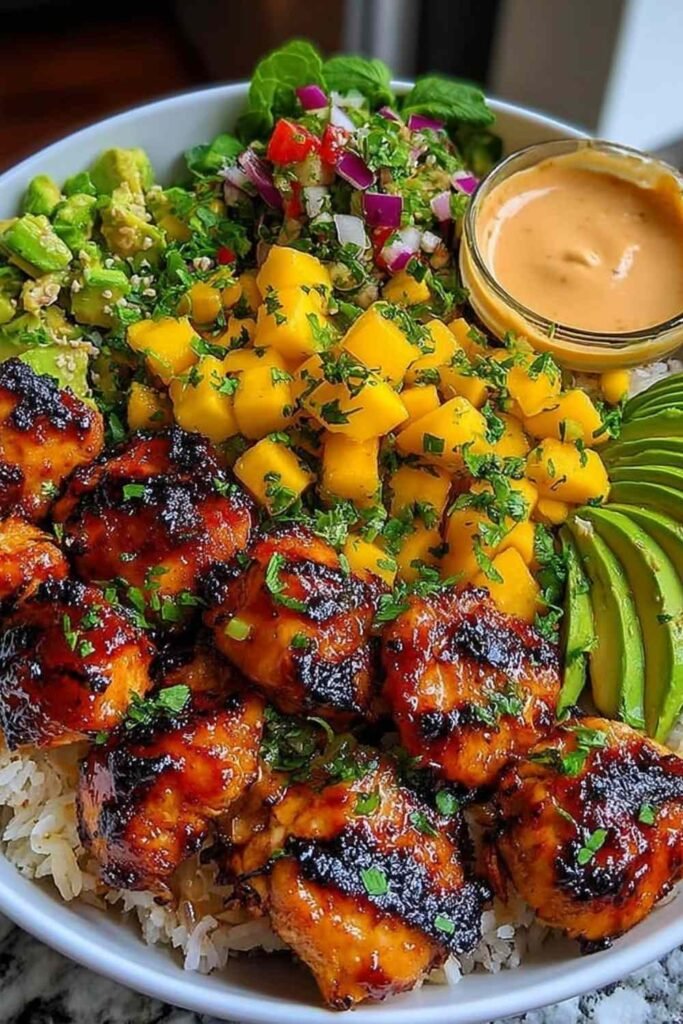 Grilled maple sriracha chicken bowl with coconut rice, fresh mango avocado salsa, and chili mayo swirl