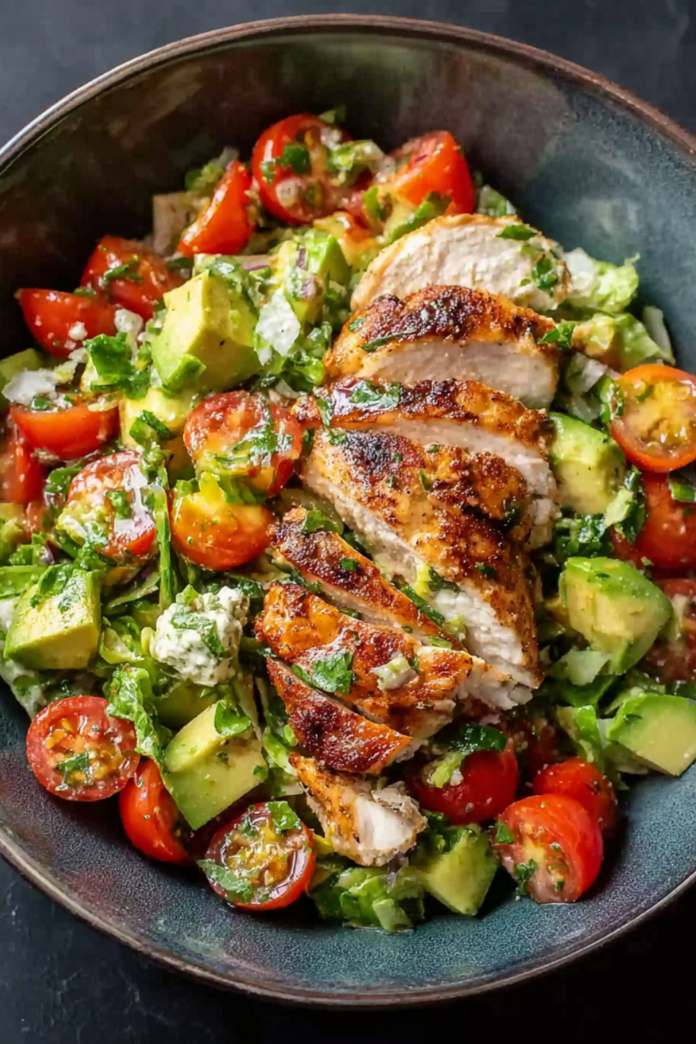 Creamy healthy avocado chicken salad with diced chicken breast, cherry tomatoes, red onion, and cilantro in a white bowl