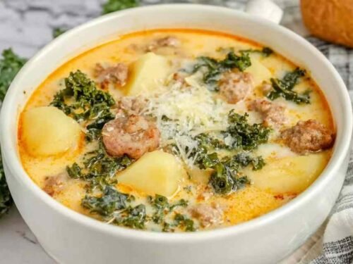 Creamy slow cooker zuppa toscana soup with Italian sausage, tender potatoes, fresh kale, and Parmesan cheese garnish in white bowl