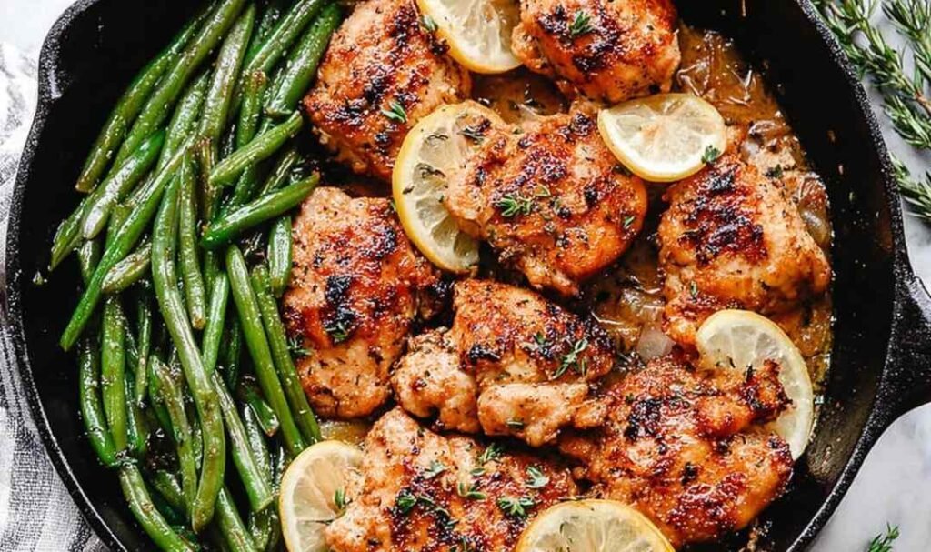 Lemon Garlic Butter Chicken and Green Beans in a cast iron skillet with garlic butter sauce, fresh parsley, and lemon slices