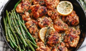 Lemon Garlic Butter Chicken and Green Beans in a cast iron skillet with garlic butter sauce, fresh parsley, and lemon slices