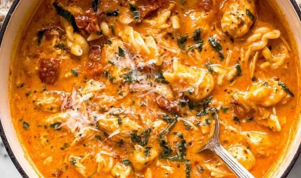 Creamy marry me chicken soup with rotini pasta, sun-dried tomatoes, and fresh basil garnished with parmesan cheese