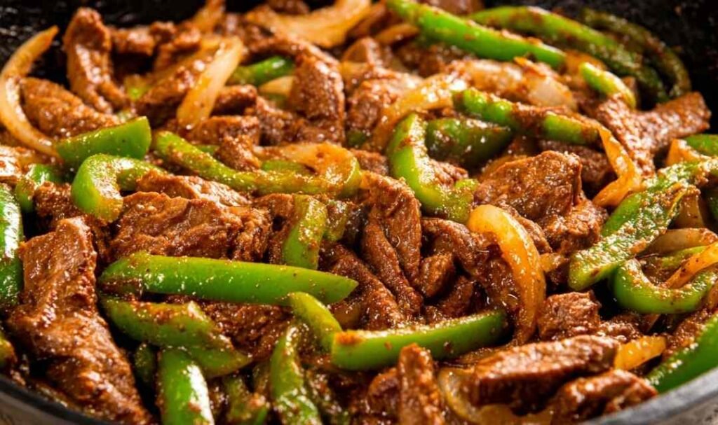 Pepper steak with tender sliced ribeye, sautéed peppers and onions in rich tomato beef sauce served over white basmati rice