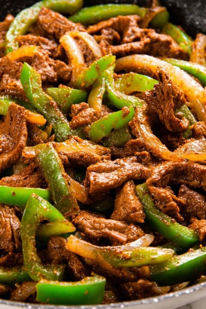 Pepper steak with tender sliced ribeye, sautéed peppers and onions in rich tomato beef sauce served over white basmati rice
