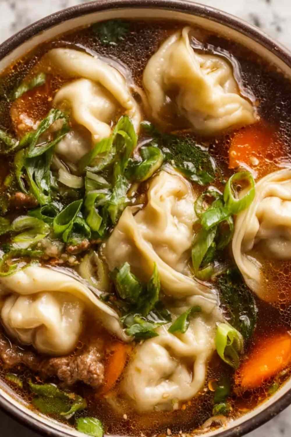 Potsticker soup in a white bowl with plump beef dumplings wilted spinach and chopped green onions in a clear golden ginger garlic chicken broth