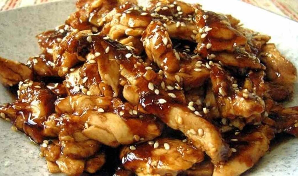 All ingredients for slow cooker teriyaki chicken combined in a crockpot before cooking, showing chicken breasts, brown sugar, soy sauce, ginger, and garlic.
