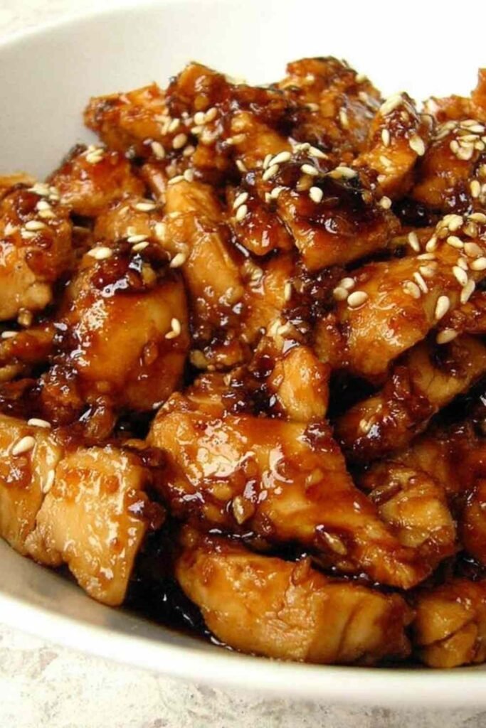 All ingredients for slow cooker teriyaki chicken combined in a crockpot before cooking, showing chicken breasts, brown sugar, soy sauce, ginger, and garlic.