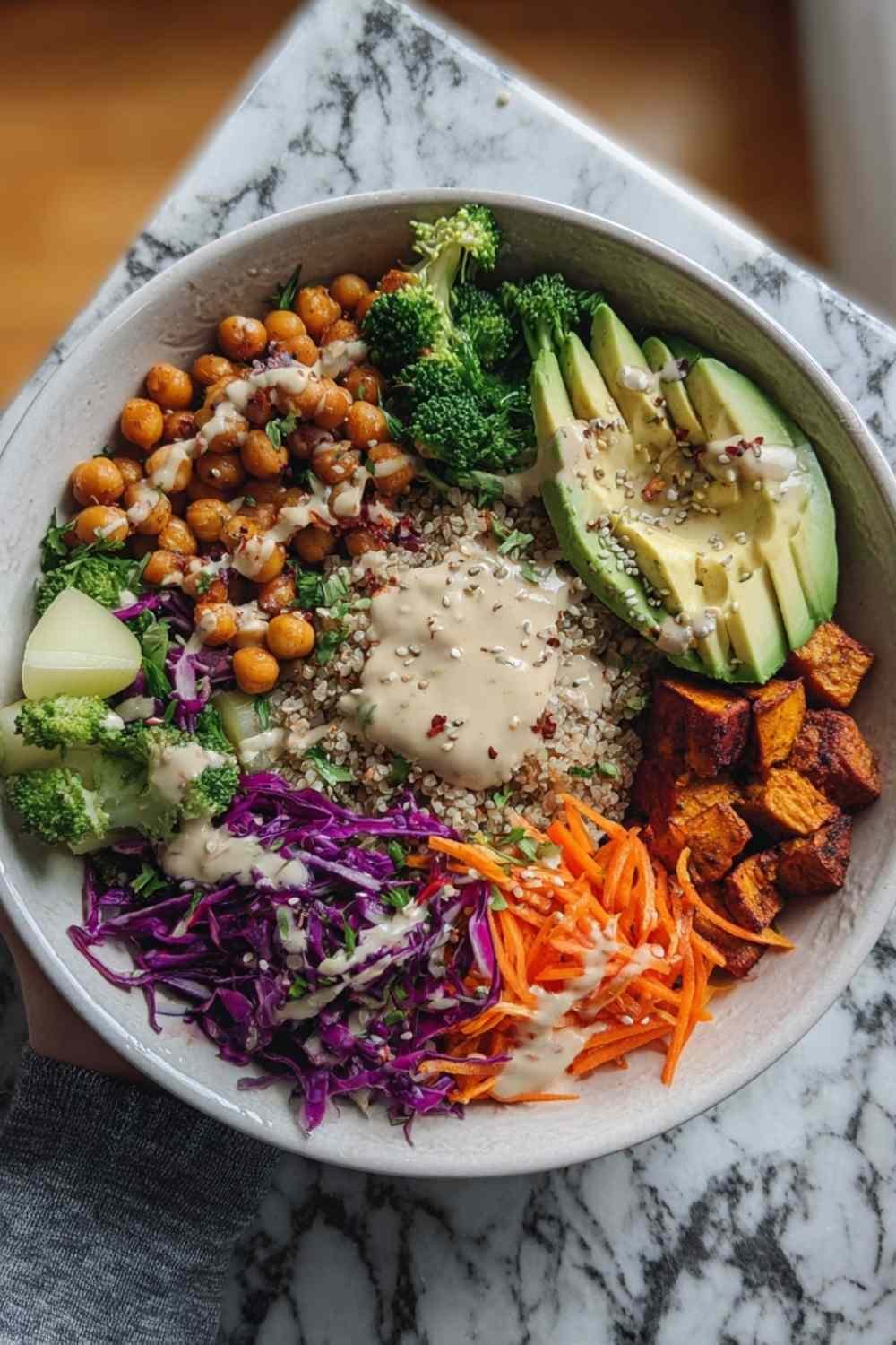 Colorful vegan buddha bowl with quinoa chickpeas roasted sweet potatoes and tahini dressing for healthy plant-based meal