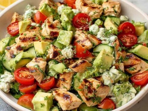 Avocado Chicken Salad Recipe in a large white bowl with cherry tomatoes, diced cucumber, fresh cilantro, and a lime wedge