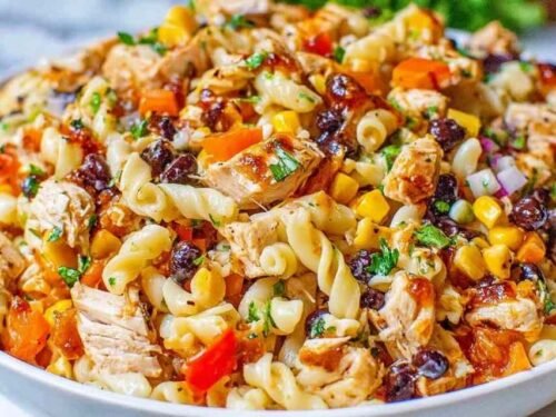 Large bowl of BBQ chicken pasta salad with shell pasta, black beans, red and orange bell peppers, corn, and cilantro tossed in creamy BBQ dressing