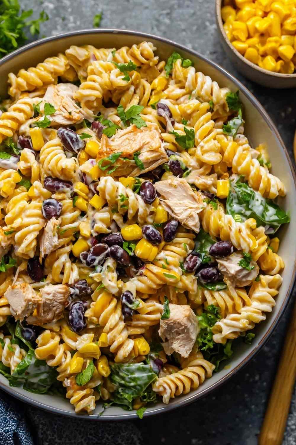 Overhead shot of BBQ Chicken Pasta Salad with shredded chicken, black beans, corn, and creamy BBQ dressing in a large white bowl