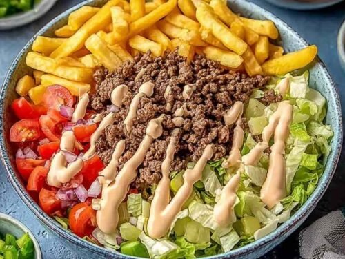 Homemade Big Mac Bowl with seasoned ground beef, shredded lettuce, cheddar cheese, and creamy special sauce in a white bowl