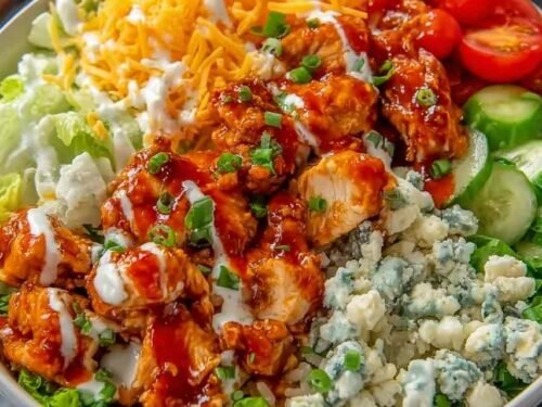 Buffalo Chicken Protein Bowl with saucy chicken over rice, cherry tomatoes, shredded cheddar, and ranch drizzle in a white bowl