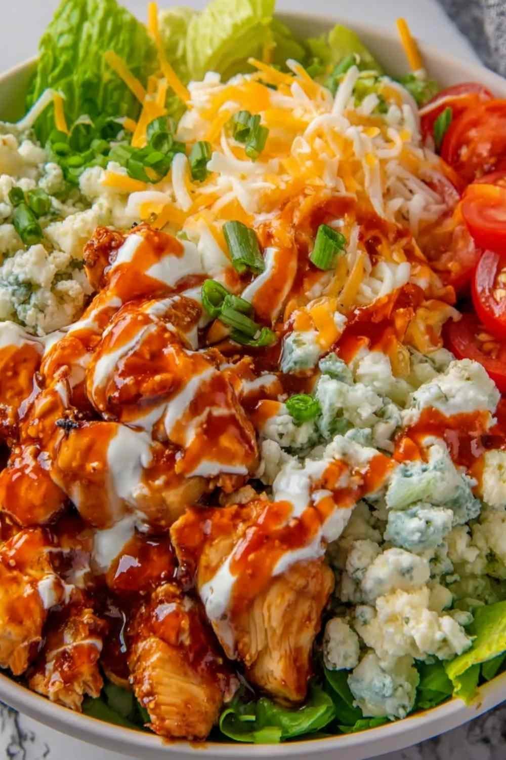 Buffalo Chicken Protein Bowl with saucy chicken over rice, cherry tomatoes, shredded cheddar, and ranch drizzle in a white bowl
