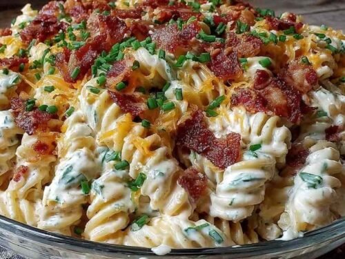 Creamy loaded pasta salad with ranch and bacon in a large white bowl with cherry tomatoes and cheddar
