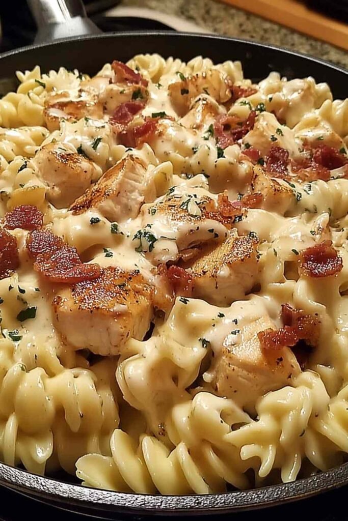 Chicken bacon ranch pasta in large skillet with creamy cheddar sauce rotini chopped bacon and cubed chicken