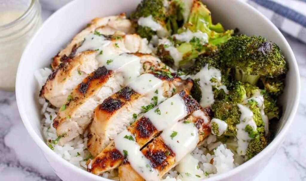 Chicken and broccoli bowls with creamy garlic sauce served over rice with fresh parsley garnish
