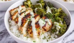 Chicken and broccoli bowls with creamy garlic sauce served over rice with fresh parsley garnish