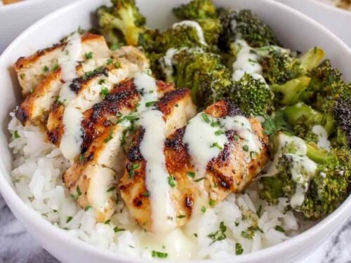 Chicken and broccoli bowls with creamy garlic sauce served over rice with fresh parsley garnish