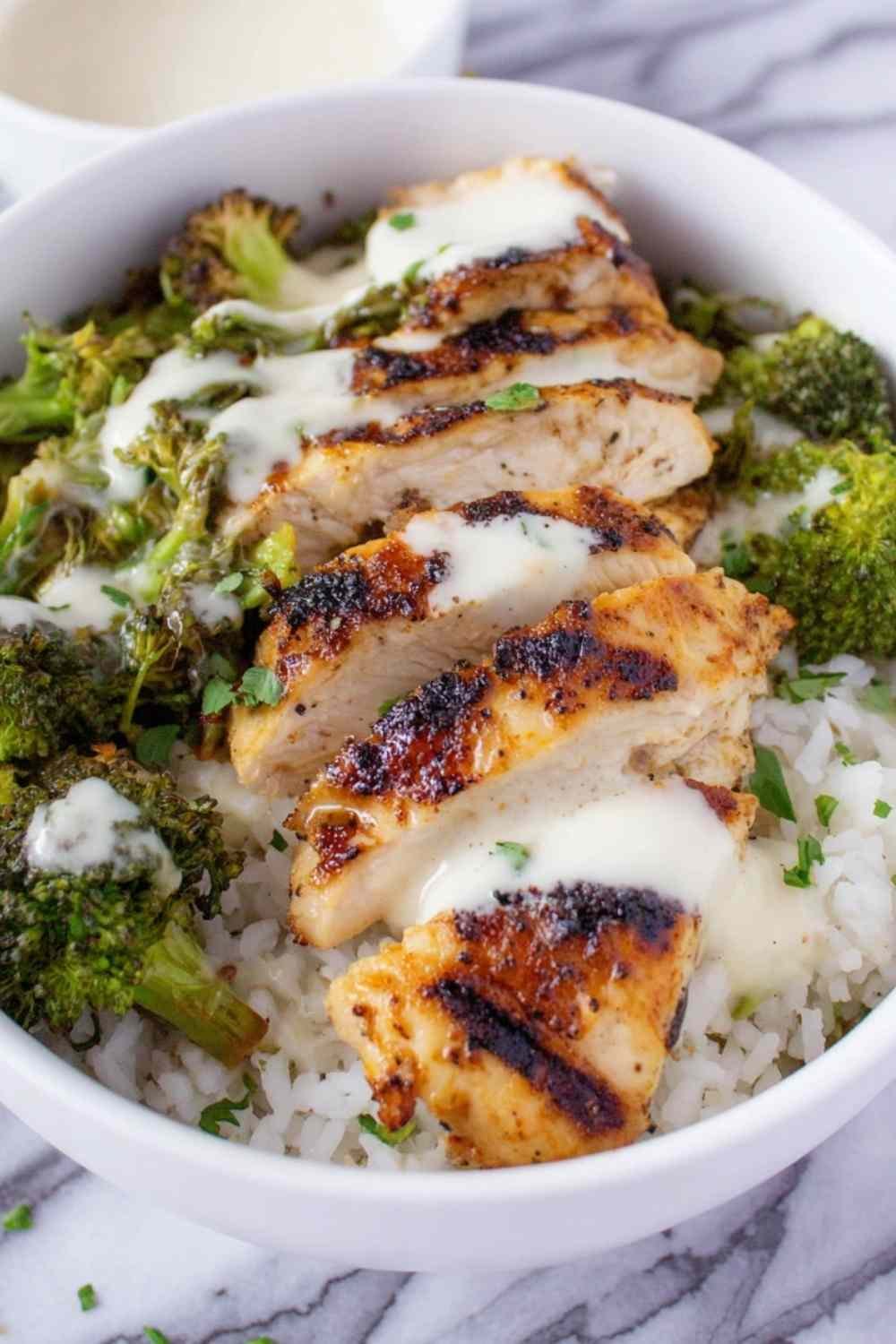 Chicken and broccoli bowls with creamy garlic sauce served over rice with fresh parsley garnish