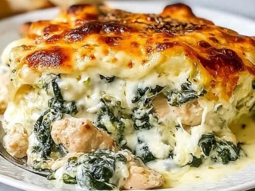 Chicken and spinach casserole with cream cheese baked golden in a white ceramic baking dish with melted mozzarella on top