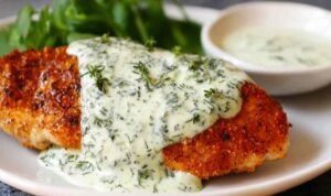 Chicken in basil cream sauce on a white plate with Parmesan cream sauce and fresh basil garnish