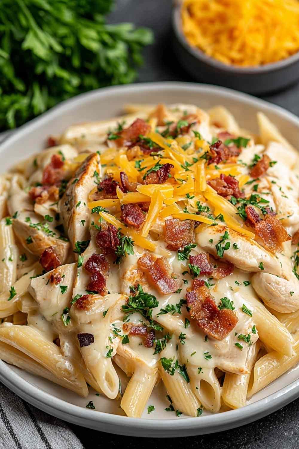 Creamy crack chicken penne in a pot with crispy bacon, shredded cheddar, and chopped green onions