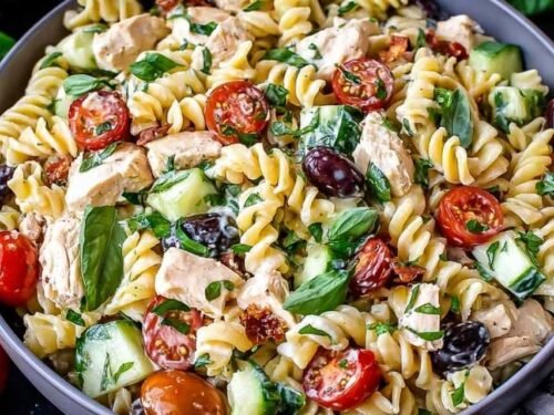 Creamy chicken pasta salad in large white bowl with avocado cherry tomatoes fresh basil grilled chicken and lemon garlic dressing