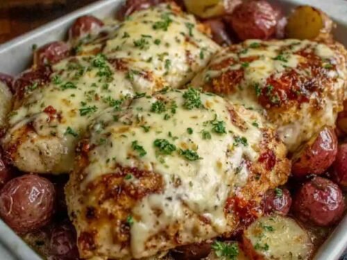 Creamy garlic cheesy chicken and potatoes in a skillet with bubbly golden mozzarella and fresh parsley