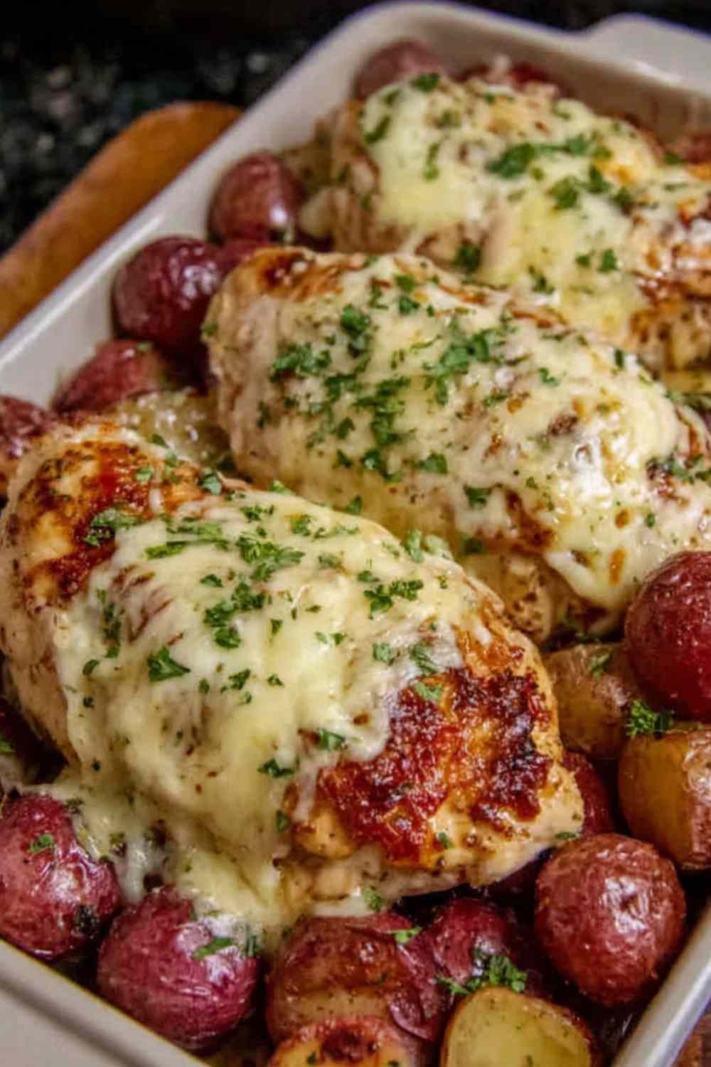Creamy garlic cheesy chicken and potatoes in a skillet with bubbly golden mozzarella and fresh parsley