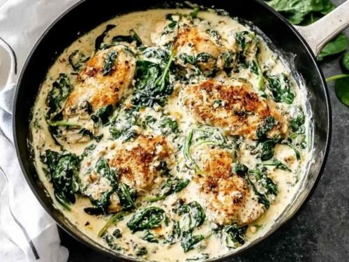 Creamy spinach chicken served on a white plate with golden chicken cutlets in a rich garlic cream sauce with wilted spinach