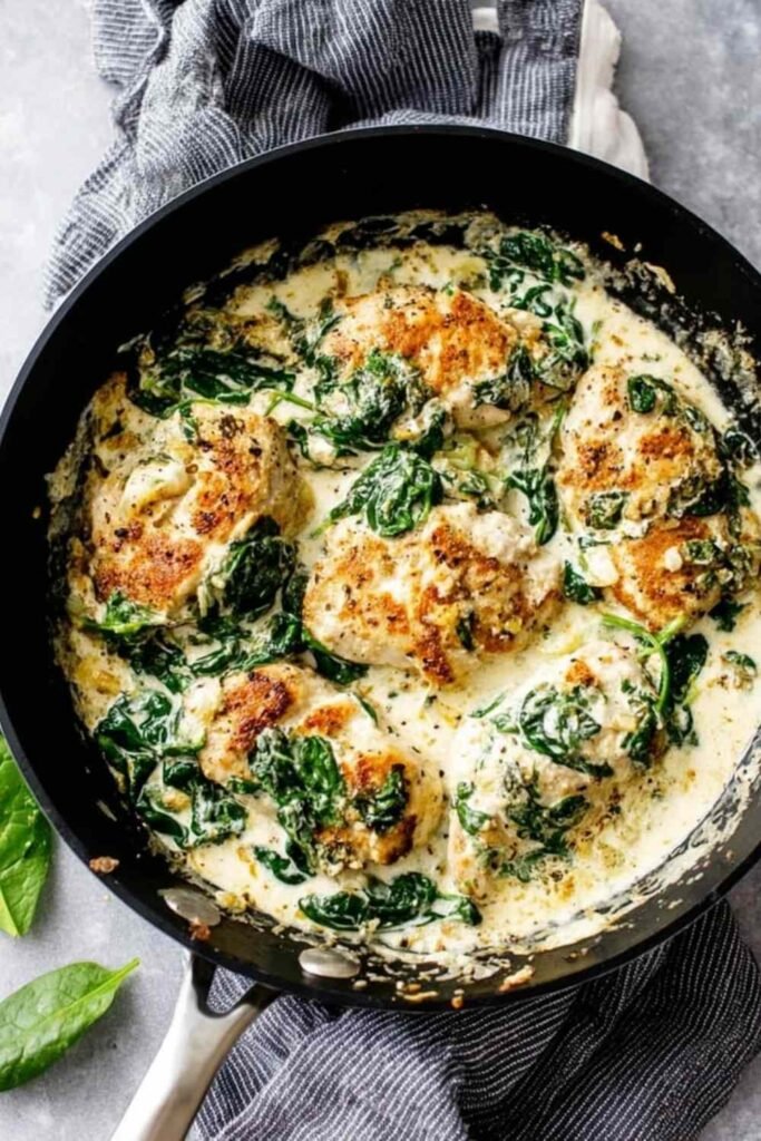 Creamy spinach chicken served on a white plate with golden chicken cutlets in a rich garlic cream sauce with wilted spinach