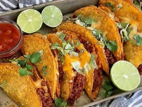 Crispy oven baked tacos with ground beef and melted cheese arranged on a baking sheet, golden and crunchy fresh from the oven
