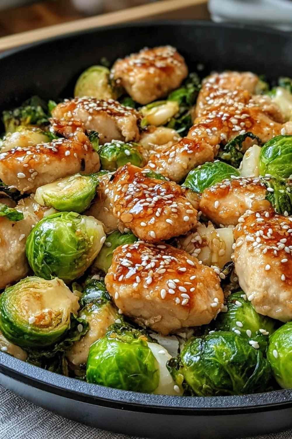 Honey garlic chicken Brussels sprouts skillet with glossy glaze and sesame seeds served in a large skillet