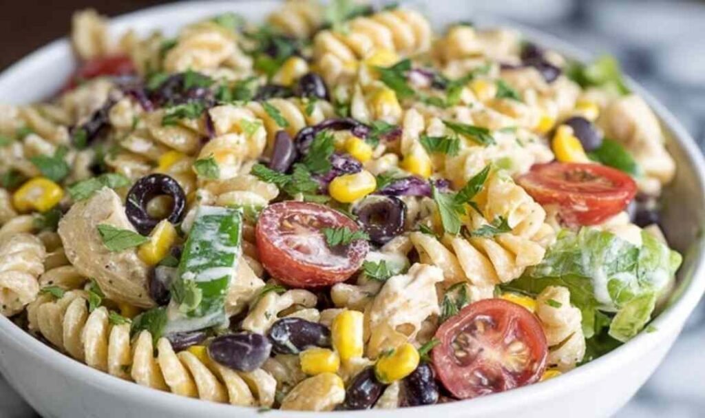 Large bowl of southwest pasta salad with rotini, grilled chicken, black beans, corn, tomatoes, and cilantro coated in chipotle ranch dressing