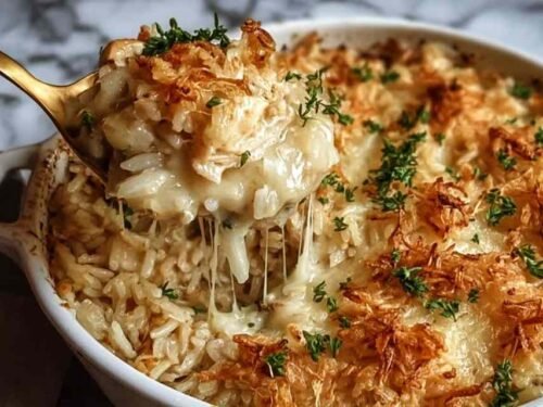 Overhead view of French Onion Chicken Rice Bake in a 9x13 baking dish with crispy golden French fried onions on top and chopped parsley garnish