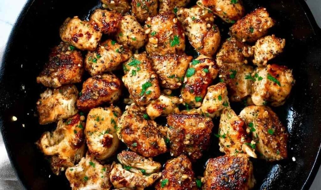 Garlic butter chicken bites in a skillet with fresh parsley and golden garlic butter sauce