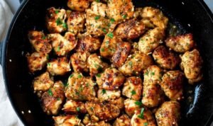 Garlic butter chicken bites in a skillet with fresh parsley and golden garlic butter sauce