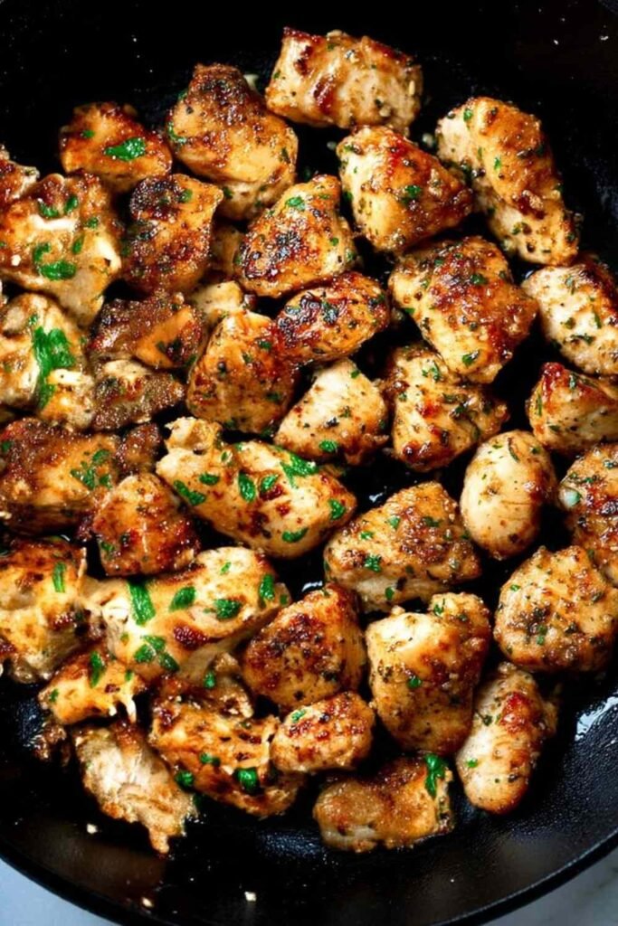 Garlic butter chicken bites in a skillet with fresh parsley and golden garlic butter sauce