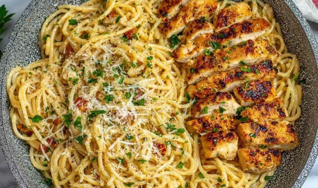 Garlic butter chicken pasta in a large skillet with sliced chicken breast, spaghetti, and Parmesan cheese garnished with fresh parsley